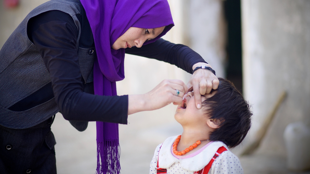 A volunteer administers an oral polio vaccine to a child.